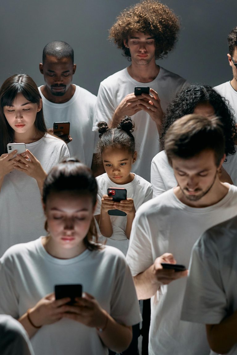 People in white t-shirts, staring at phones.